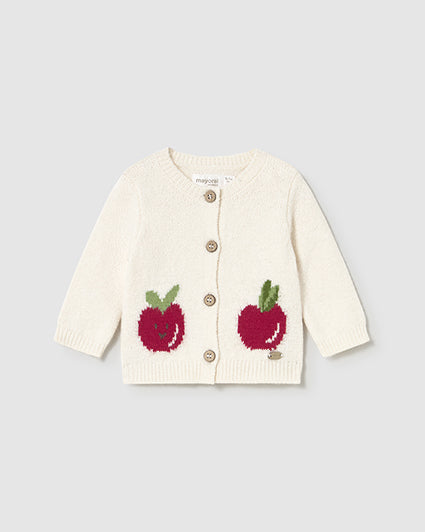 White cardigan with red apple designs on a light gray background