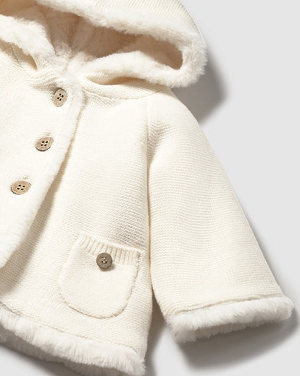 Close-up of a cream-colored children's coat with buttons on a light background