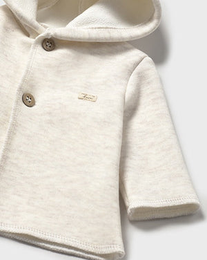 White baby hoodie with button details on a light gray background