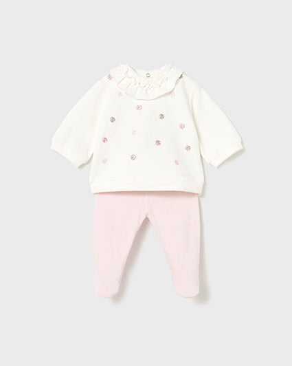 Baby outfit with white top and pink pants on a light gray background