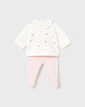 Baby outfit with white top and pink pants on a light gray background