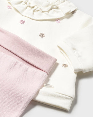 Baby outfit with pink pants and white top on a light gray background