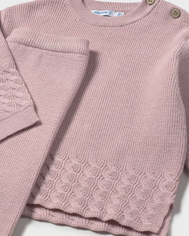 Pink knitted sweater with cable pattern on a white background