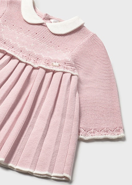 Pink knitted dress with lace details on a light gray background