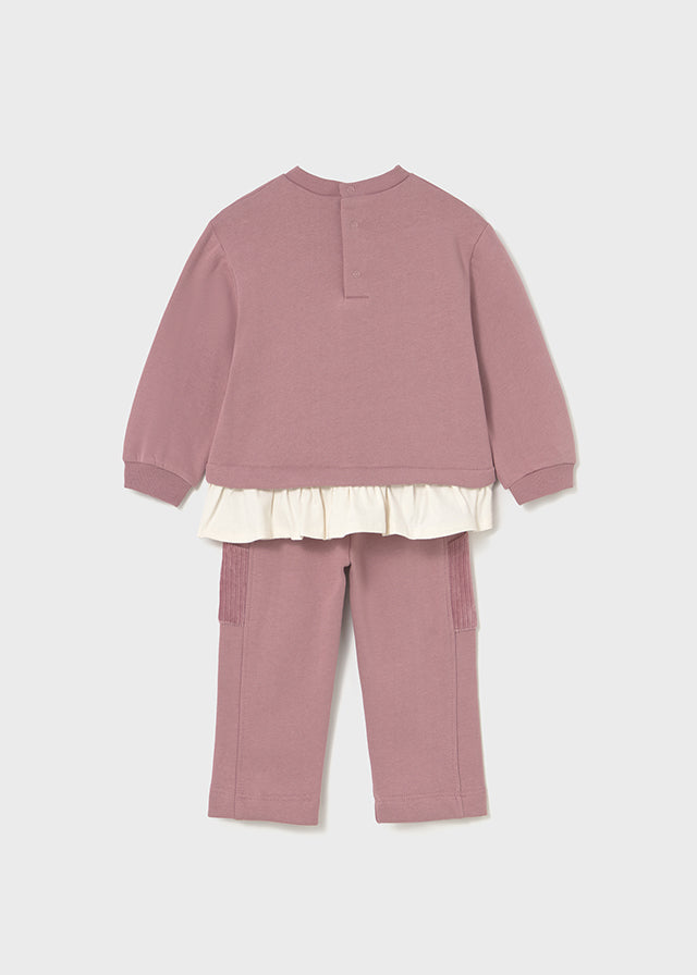 Pink children's outfit with a white ruffled top on a light gray background