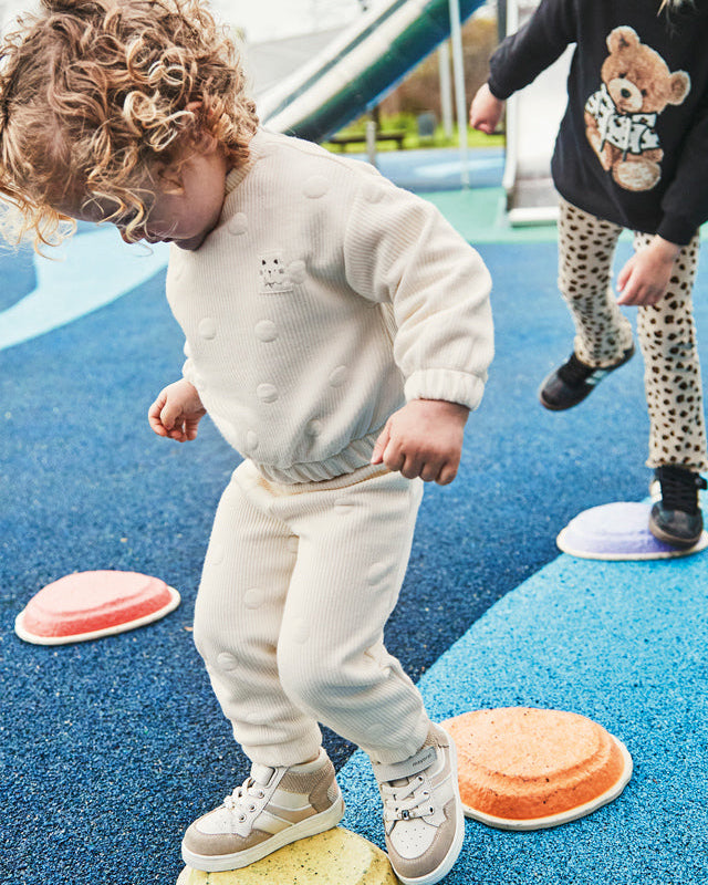 Children playing on playground equipment with a slide in the background
