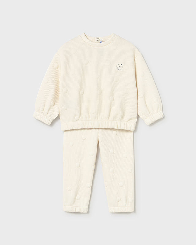 Cream-colored sweater and pants set on a light gray background