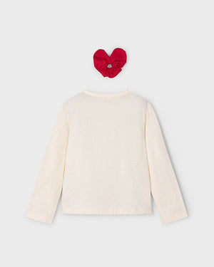 White long-sleeve top with a red heart-shaped hair accessory on a light gray background