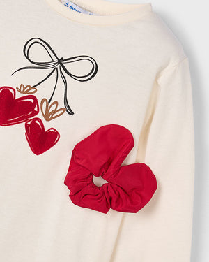 Beige sweatshirt with red hearts and bow design, paired with a red scrunchie.