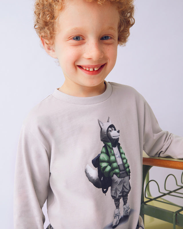 Child wearing a sweatshirt with a graphic design of a monkey in a green vest on a plain background
