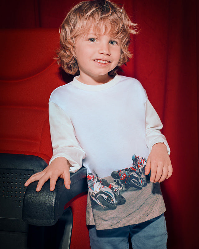 Child wearing a white sweatshirt with a graphic design against a red background