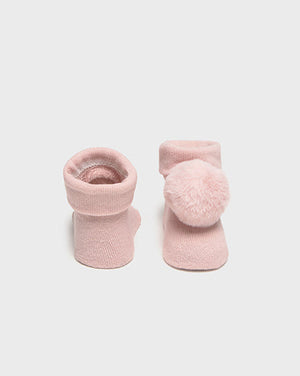 Pair of pink baby socks with pom-poms on a light gray background