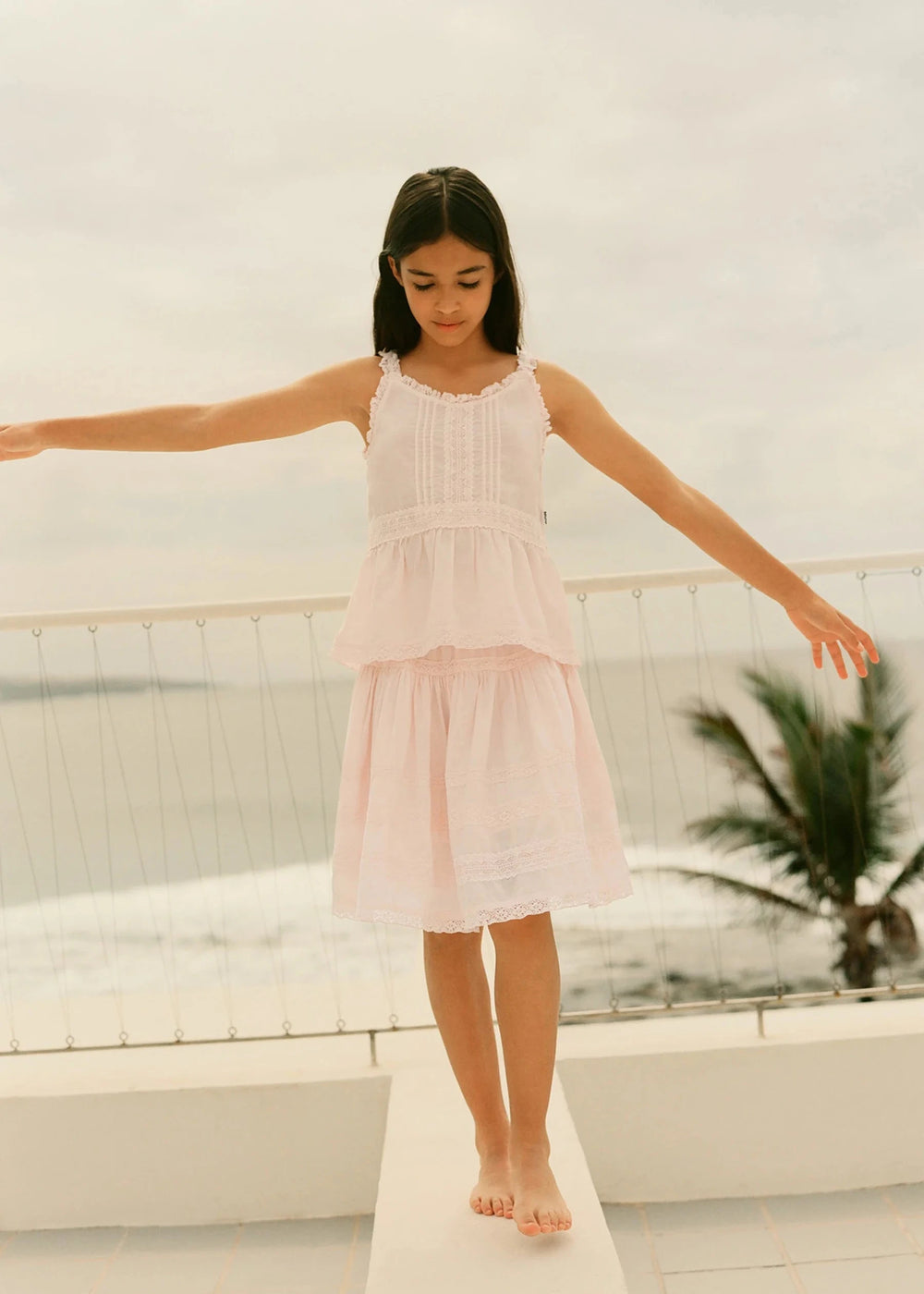 Young girl in a pink dress standing on a white platform with a blurred background