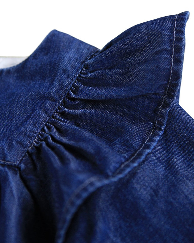 Close-up of a blue denim dress with ruffled collar on a white background