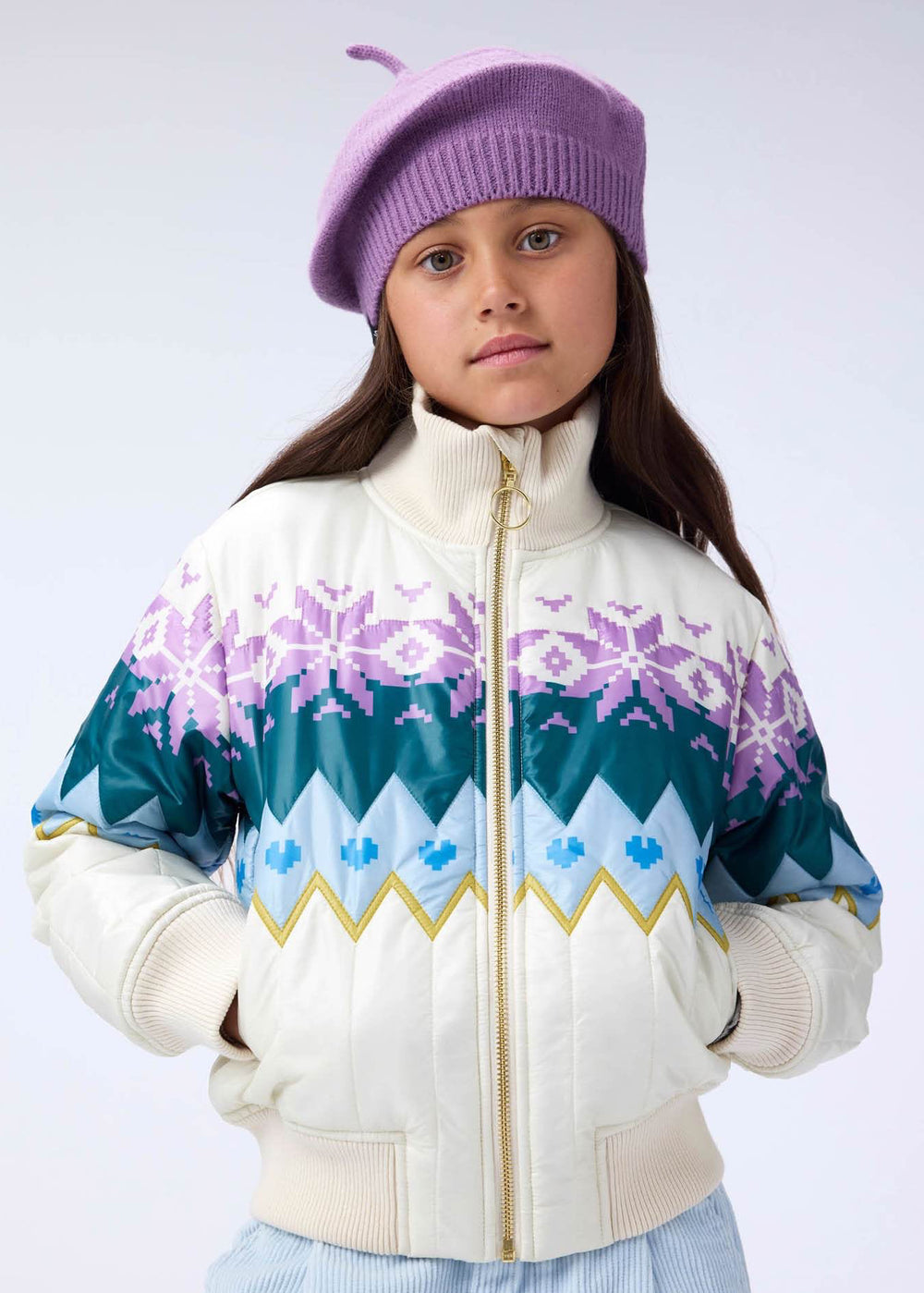 Young girl wearing a colorful jacket with snowflake patterns on a white background