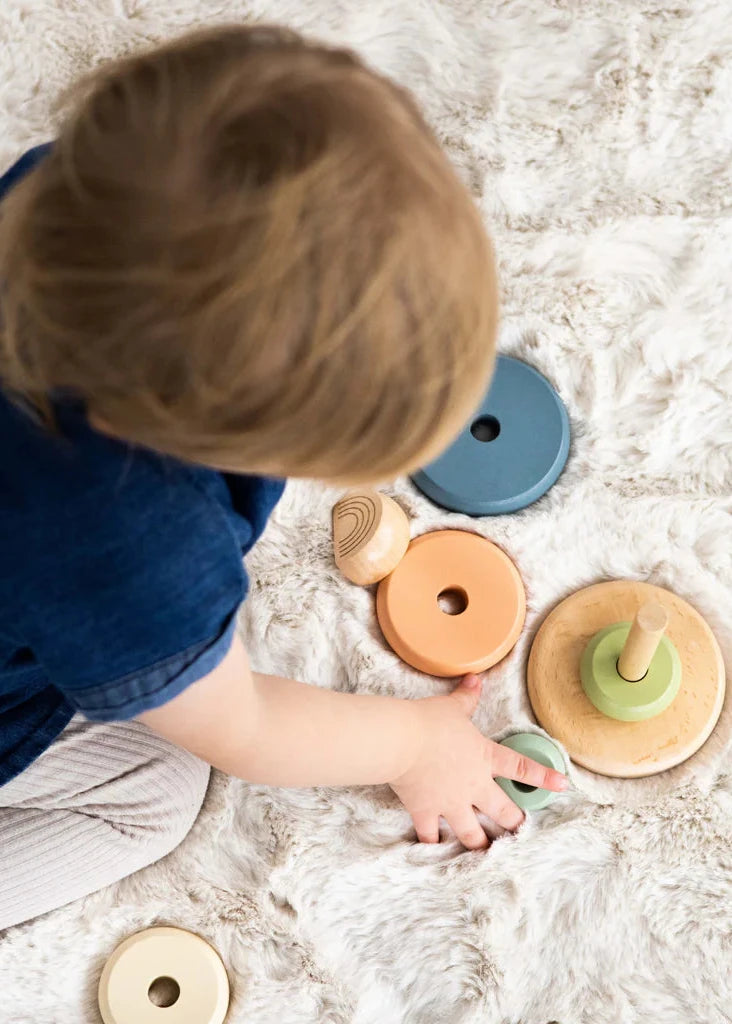 Child playing with wooden toys on a soft surface