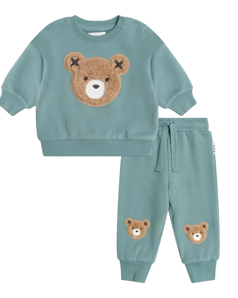 Children's teal sweatshirt and pants set with bear face designs on a white background