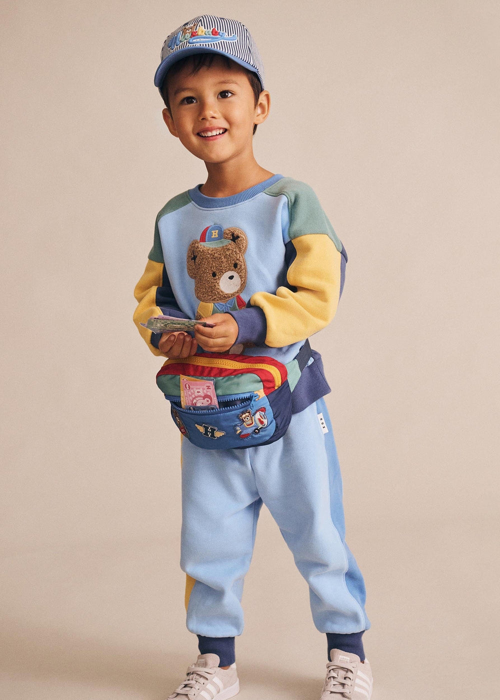 Child wearing a colorful outfit with a teddy bear design on a beige background