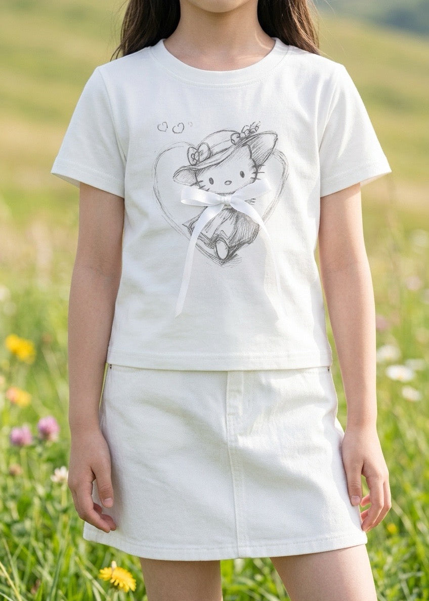 Child wearing a white t-shirt with a graphic design in a grassy field