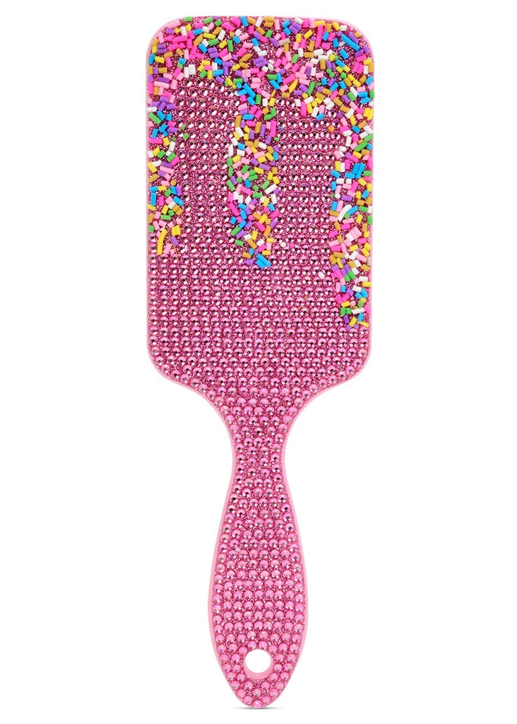 Pink paddle brush with colorful sprinkles on a white background
