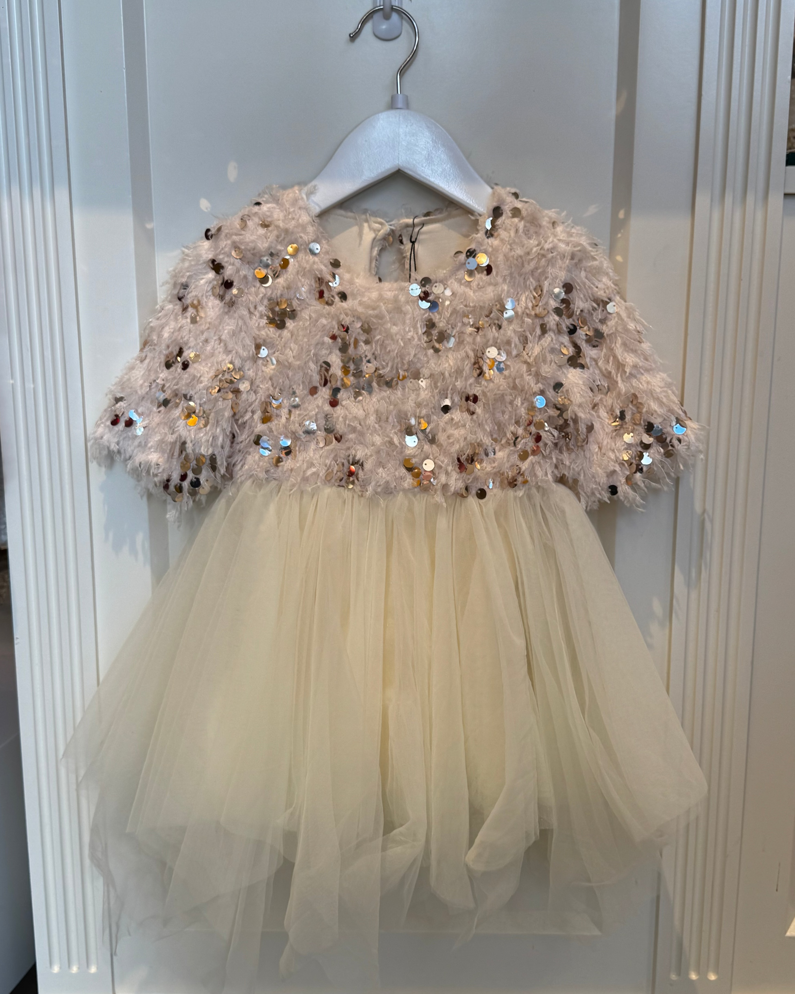 Children's dress with sequined top and tulle skirt on a hanger.
