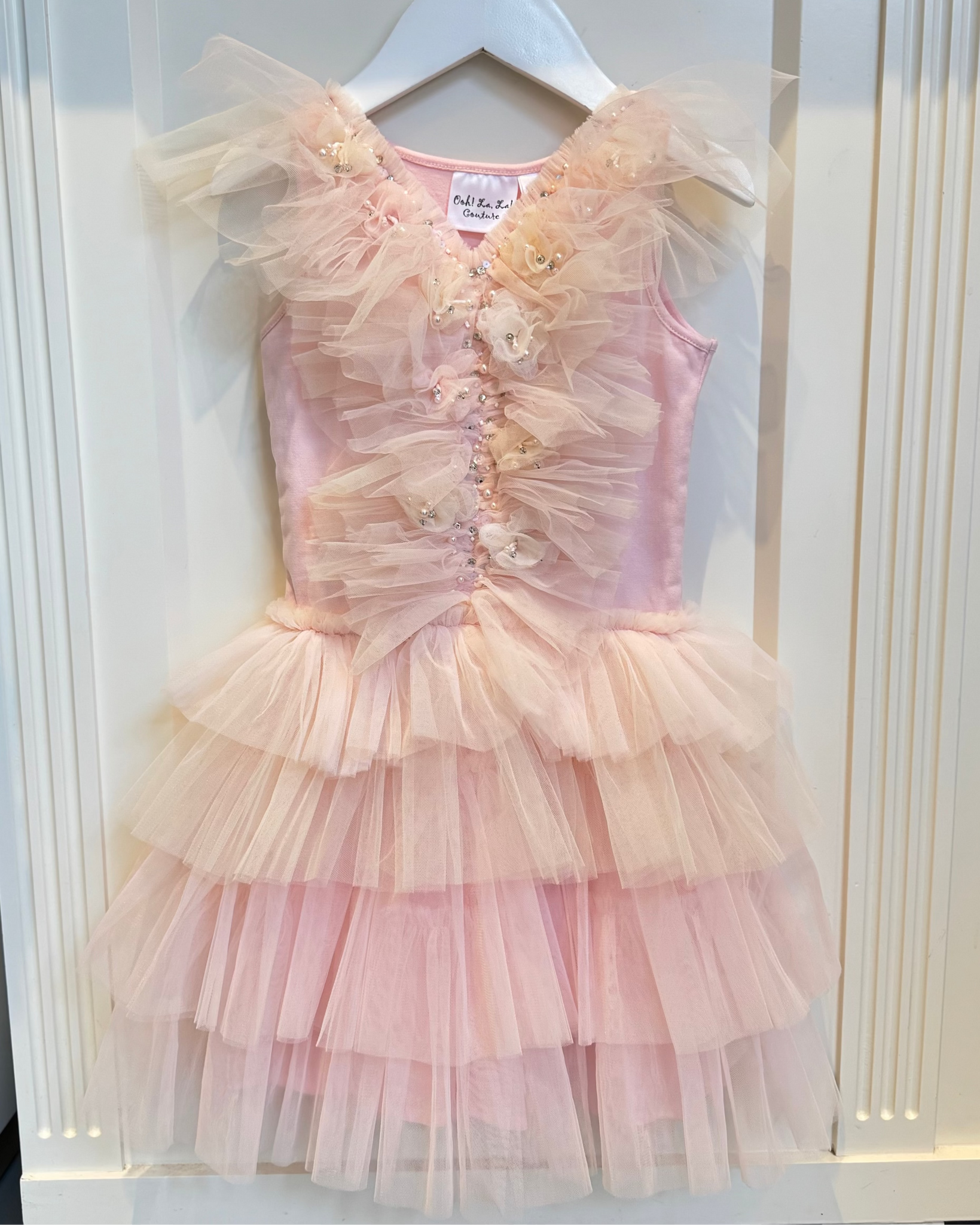 Pink tiered dress on a hanger against a white background