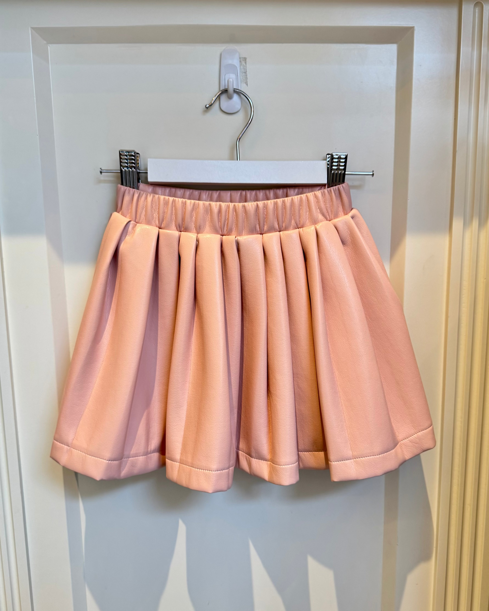 Pink skirt on a hanger against a white wall