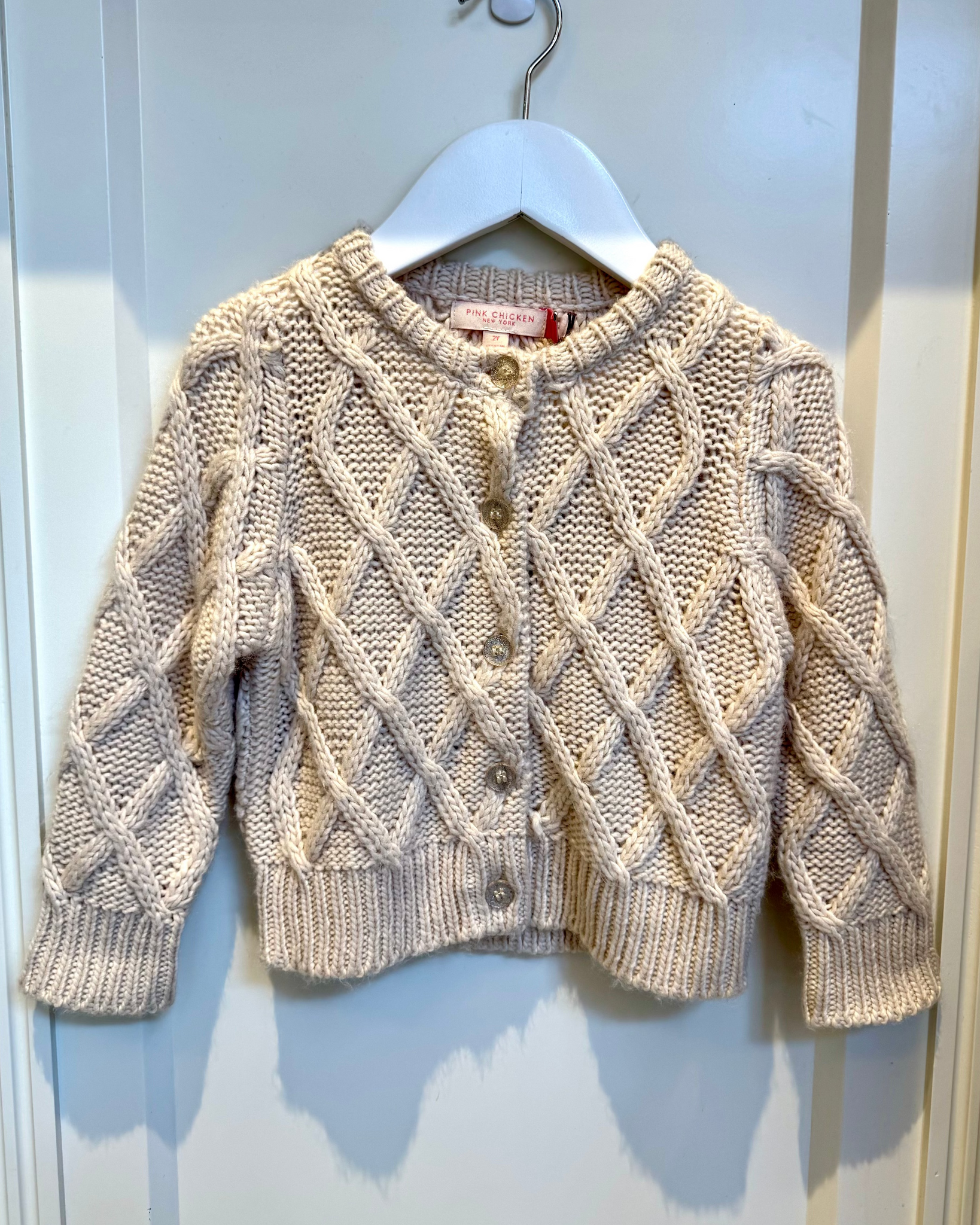 Knitted cardigan on a hanger against a white background