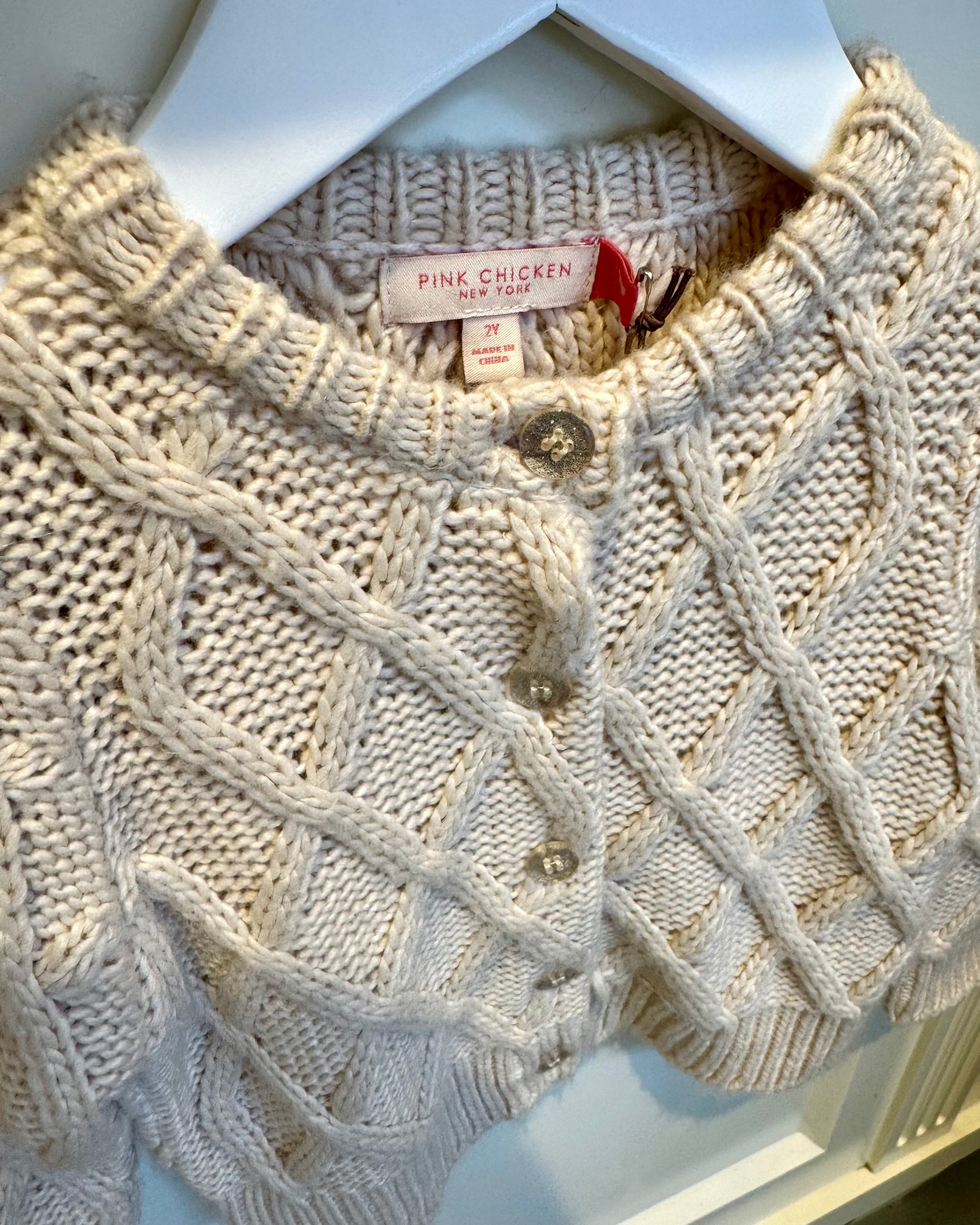 Beige knitted sweater with a brand tag on a white background