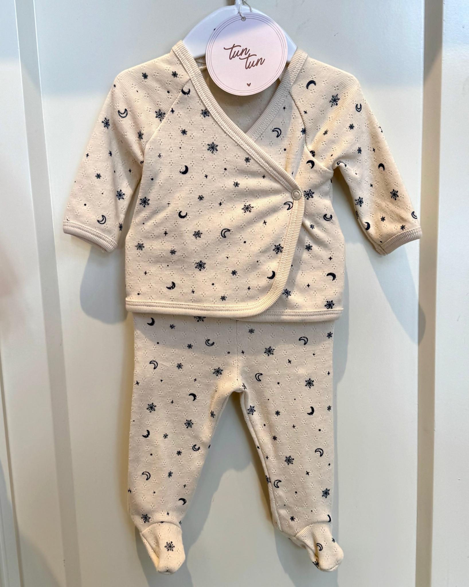 Baby outfit with long-sleeve top and pants on a hanger against a white background