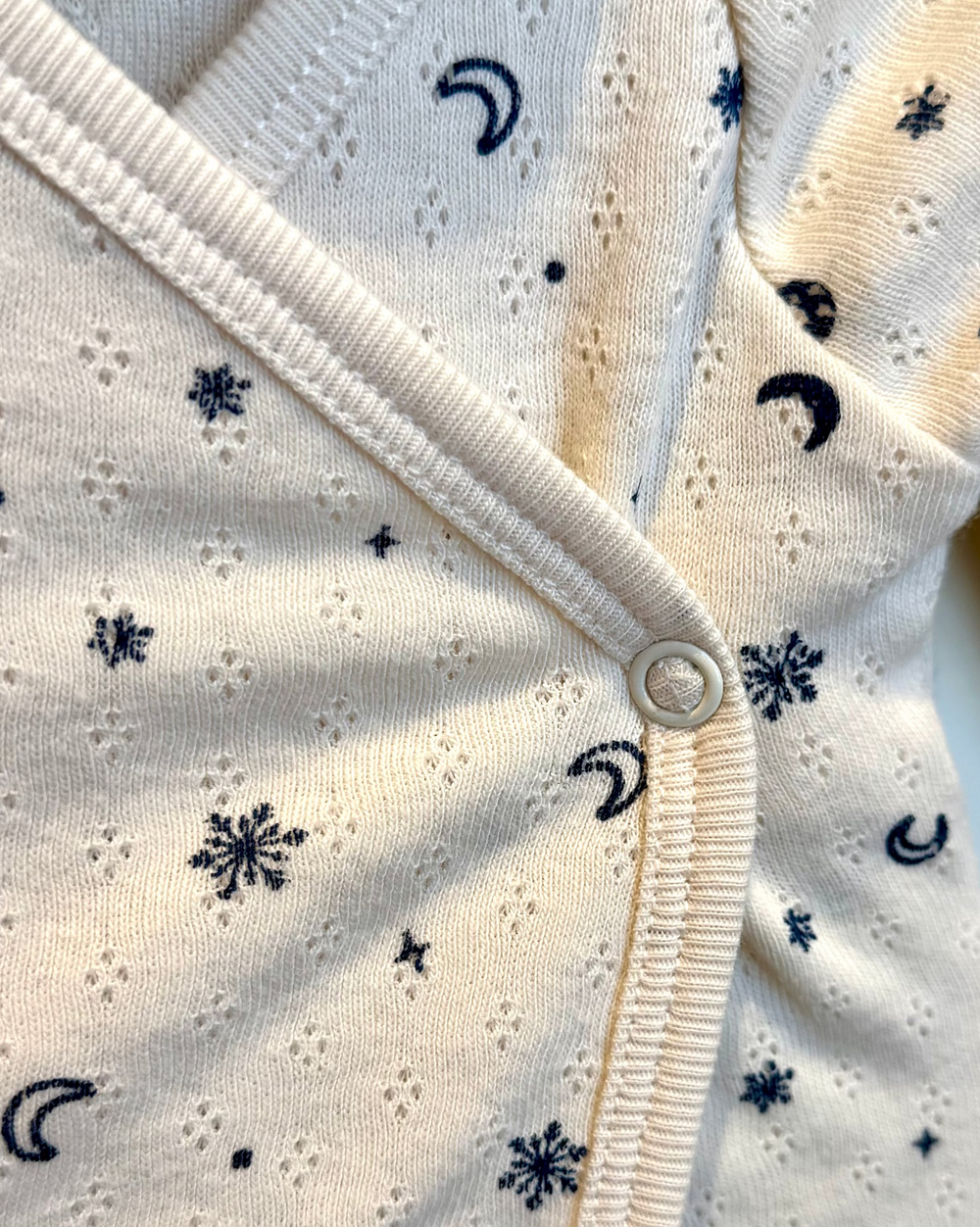 Close-up of a baby outfit with star and moon pattern on a white background
