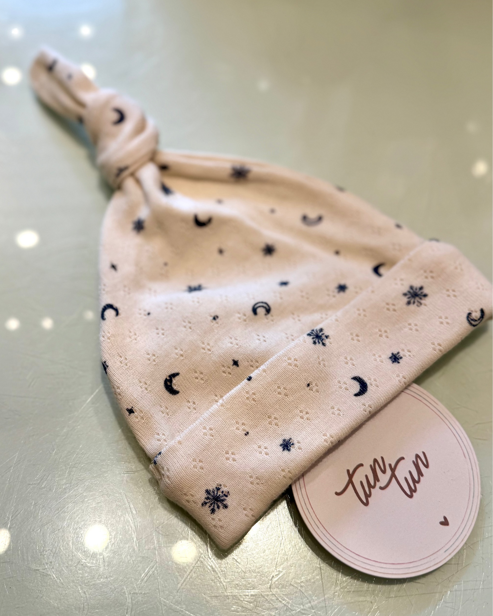 Baby hat with star and moon pattern on a light surface