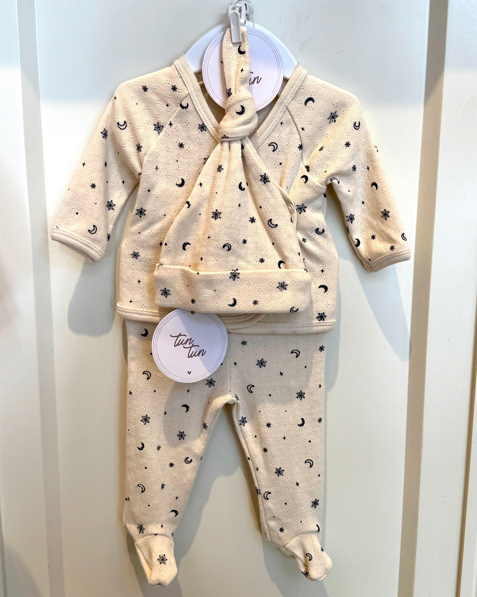 Baby outfit with top and pants hanging on a hook against a white background