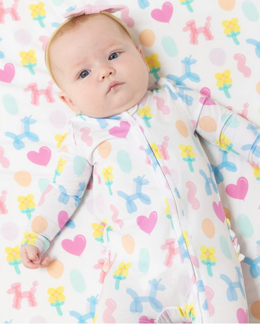 Baby lying on a colorful patterned blanket wearing a matching outfit.