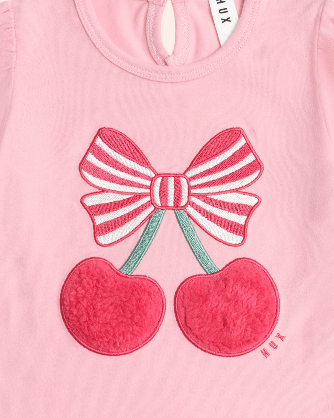 Pink shirt with a bow and cherry design, brand 'HUX' visible.
