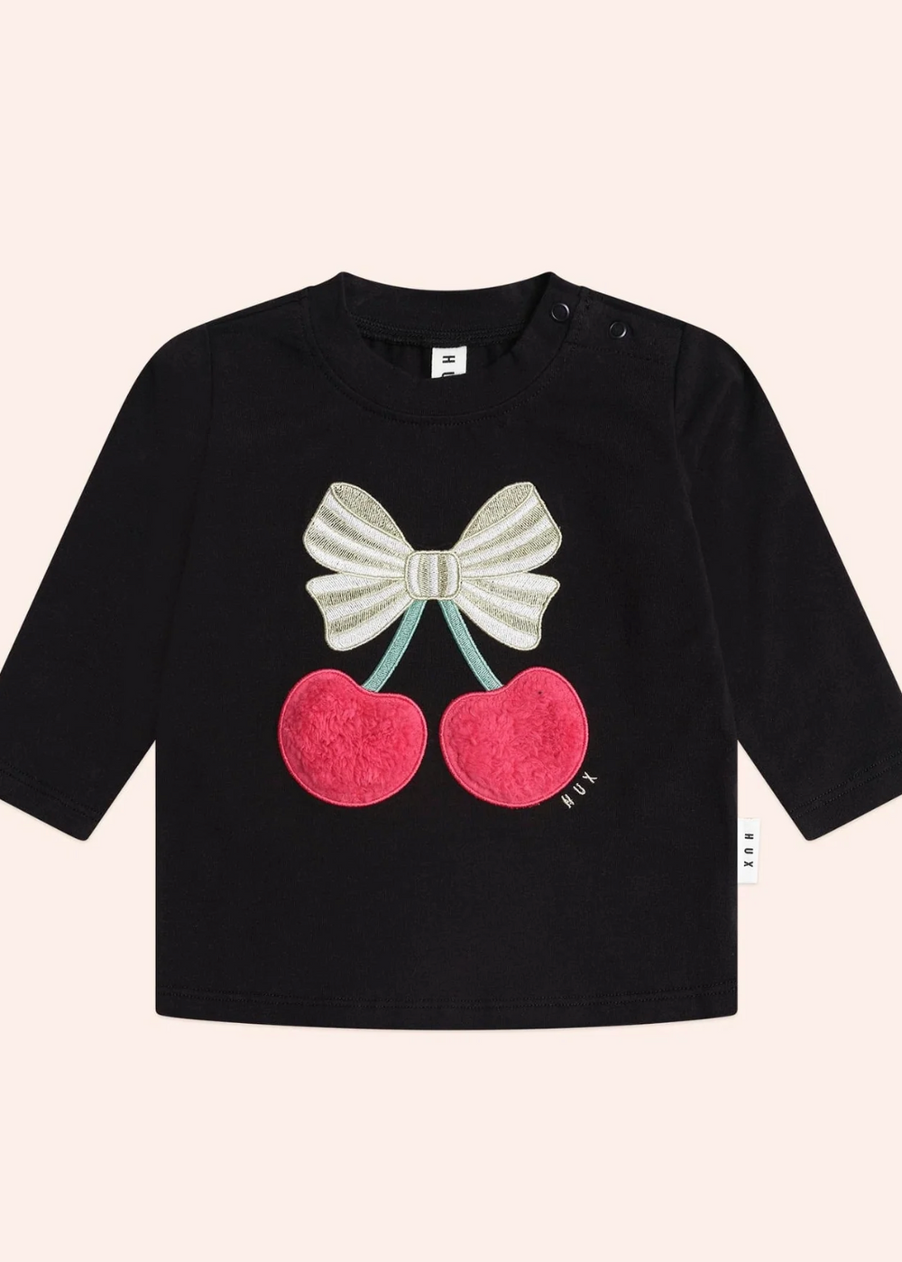 Black long-sleeve shirt with cherry and bow design on a beige background