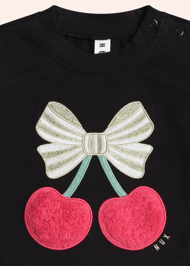 Black shirt with a bow and cherry design on a plain background