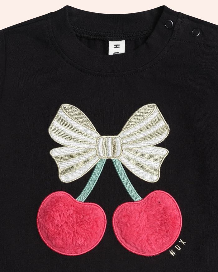 Black shirt with a bow and cherry design on a plain background