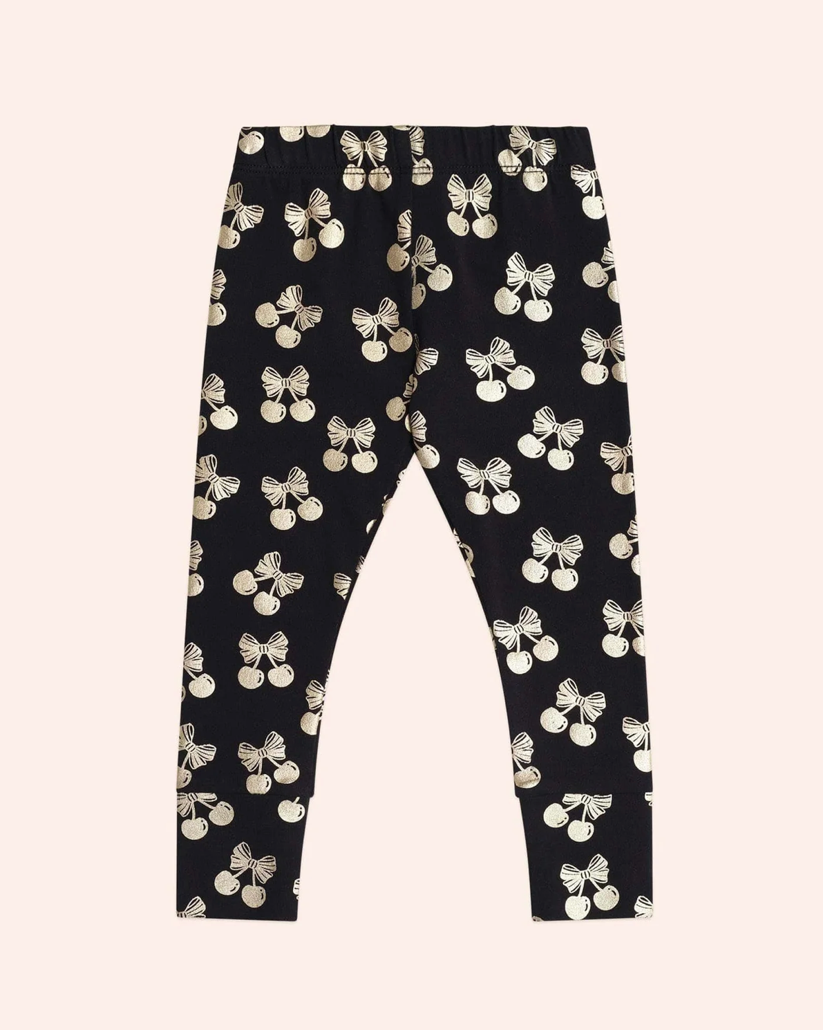 Black leggings with white bow pattern on a beige background