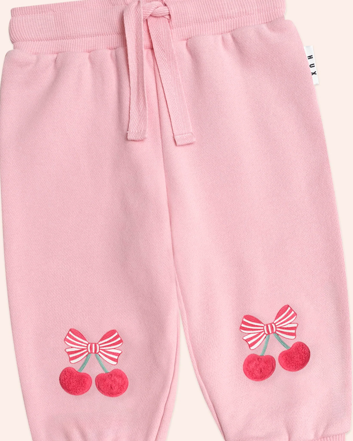 Pink children's pants with cherry and bow designs on a white background