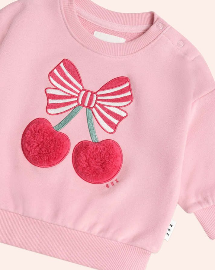Pink sweater with cherry and bow design on a white background
