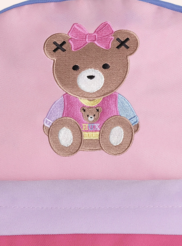 Pink apron with a teddy bear design and pink bow on a pink background