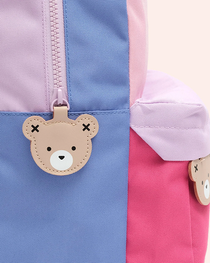 Color-blocked jacket with a bear-shaped patch on a light pink background