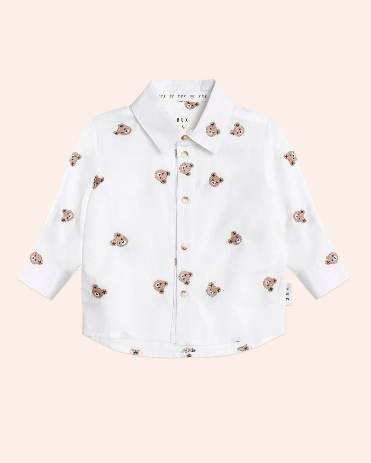 White shirt with teddy bear appliqués on a light pink background
