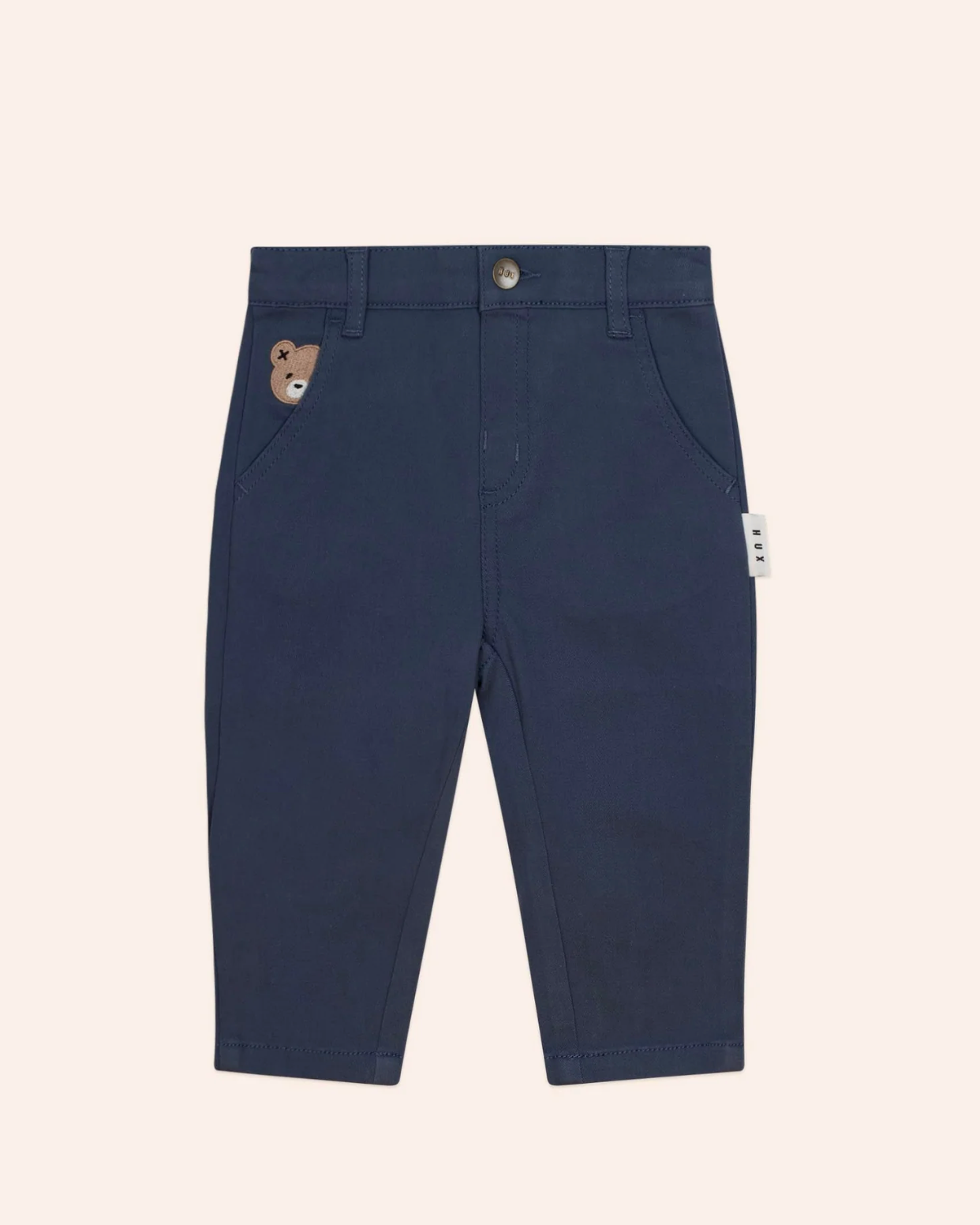 Navy blue pants with a bear patch on a beige background