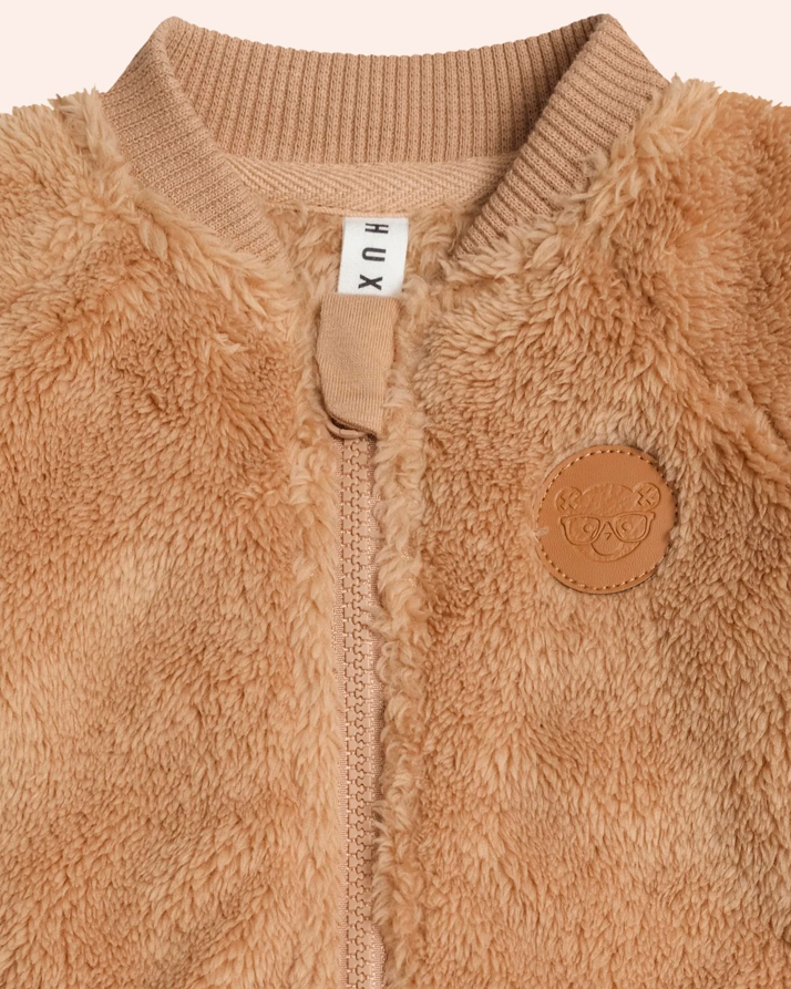 Close-up of a brown fleece jacket with a brand label on a beige background