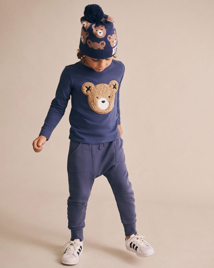 Child wearing a navy blue outfit with a teddy bear design on a beige background