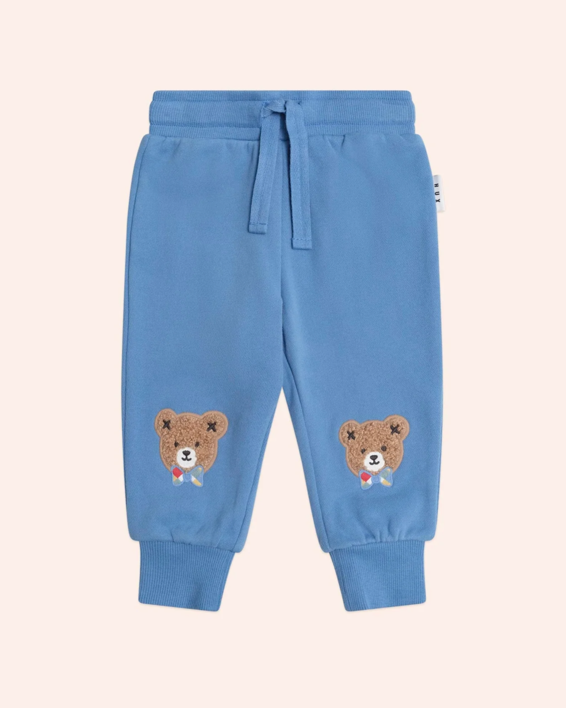 Blue children's sweatpants with bear designs on a beige background