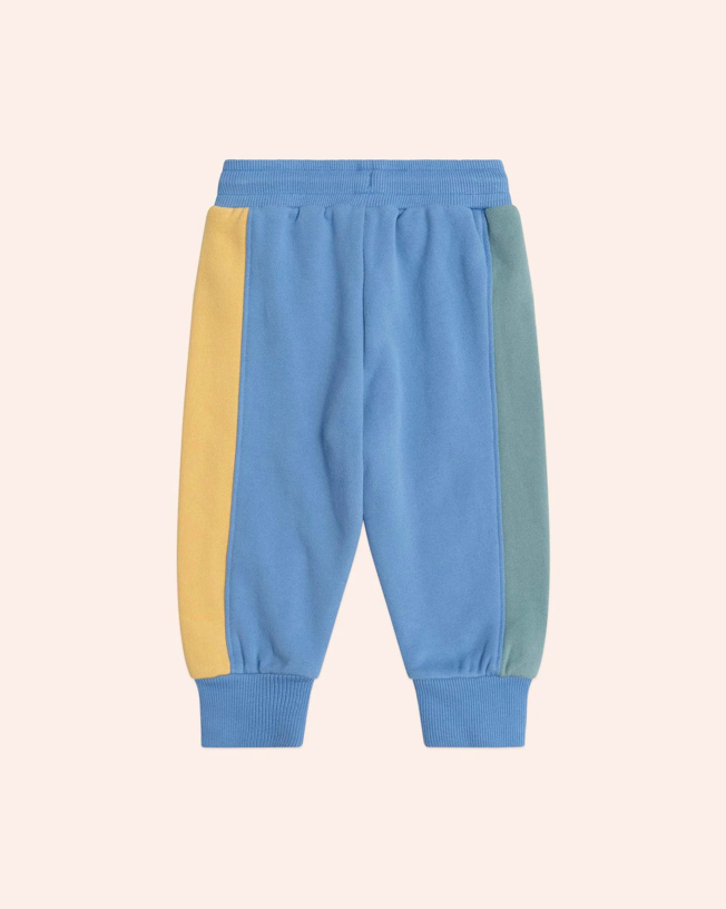 Blue sweatpants with color-blocked sides on a beige background