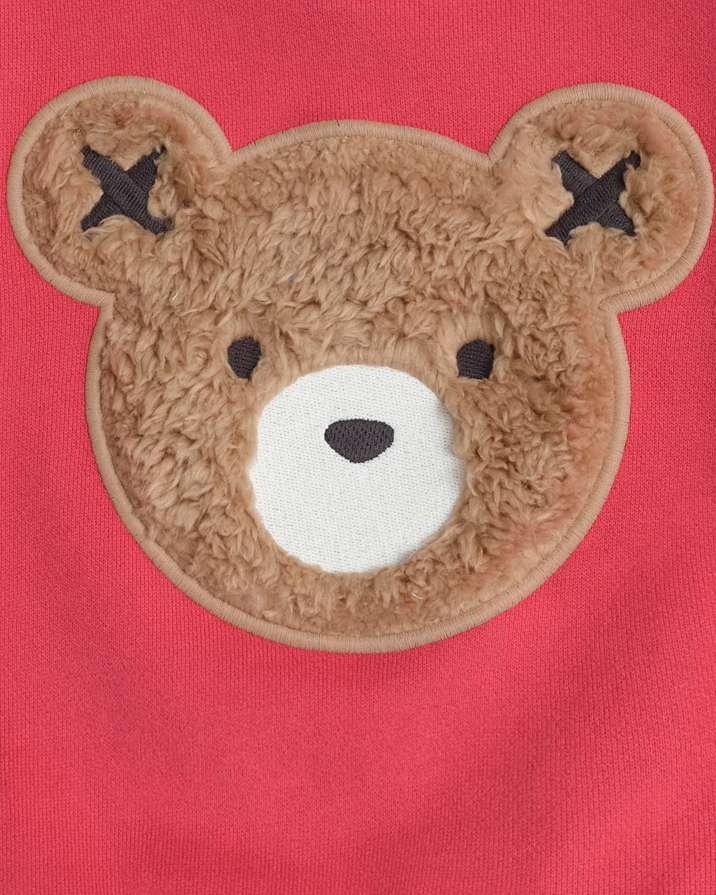 Close-up of a teddy bear face patch on a red background